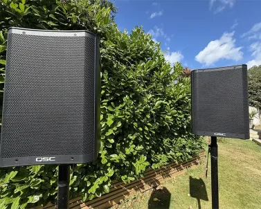 Battery Operated PA speakers with their stands in a garden setting