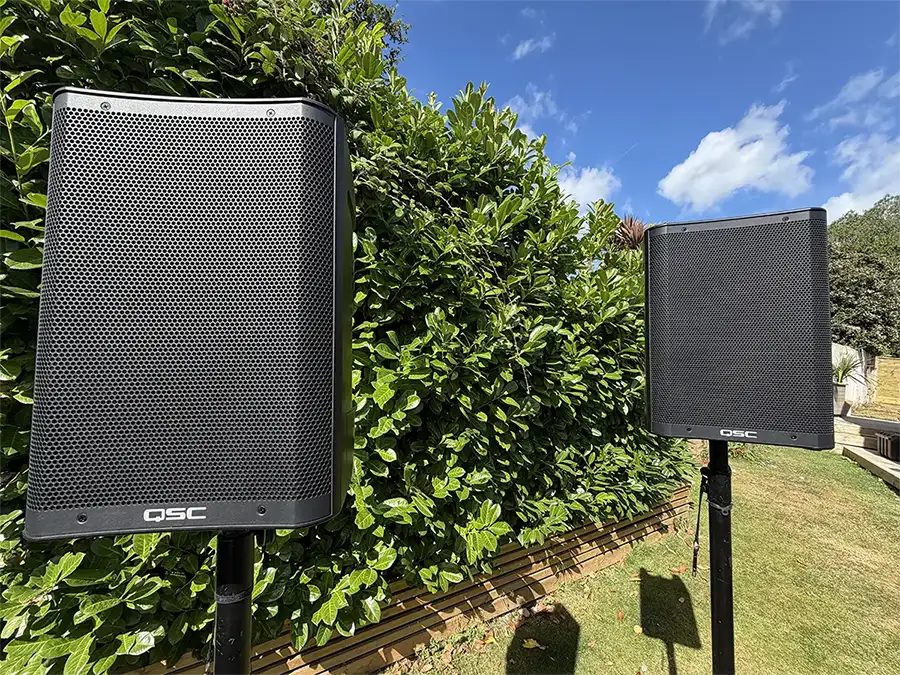 Battery Operated PA speakers with their stands in a garden setting